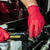 A pair of hands wearing red gloves while working on an engine.