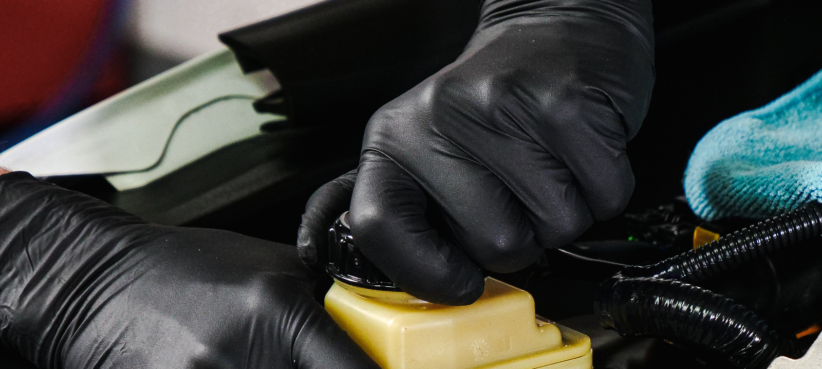 A pair of gloved hands working on an engine. 