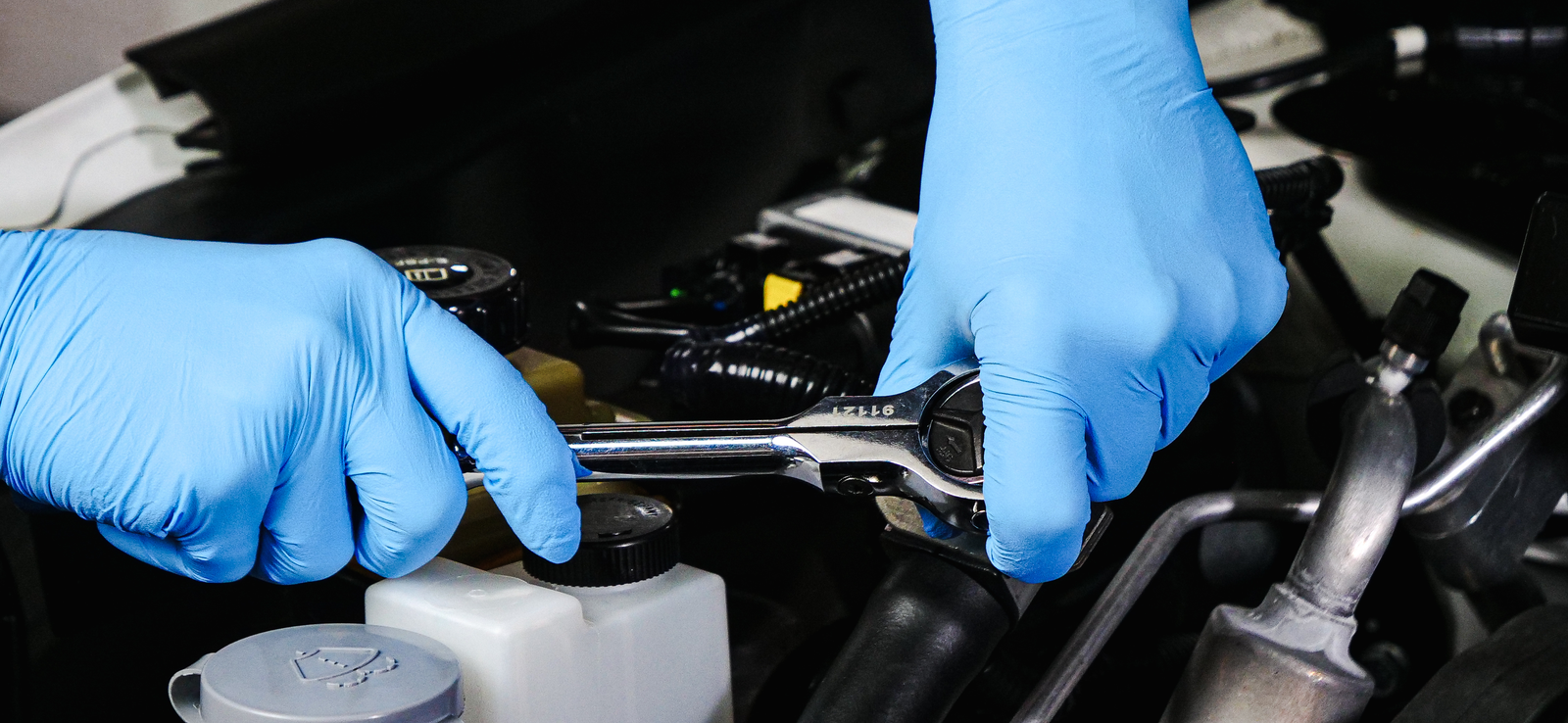 A pair of gloved hands using a tool