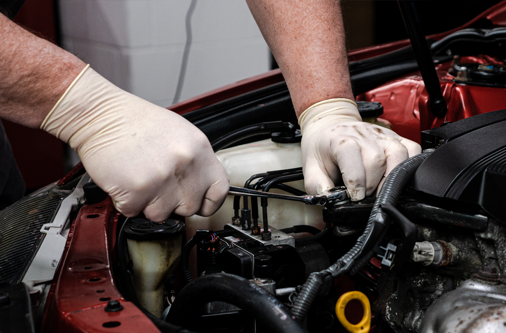 A pair of hands wearing latex gloves while working on an engine.